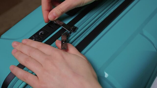 Secure suitcase with combo lock, Hands set combination on teal suitcase with textured surface, Closeup of hands adjusting numeric lock on stylish teal travel suitcase