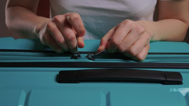 Secure suitcase with combo lock, Hands set combination on teal suitcase with textured surface, Closeup of hands adjusting numeric lock on stylish teal travel suitcase