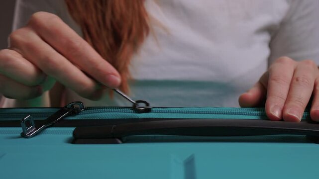 Secure suitcase with combo lock, Hands set combination on teal suitcase with textured surface, Closeup of hands adjusting numeric lock on stylish teal travel suitcase