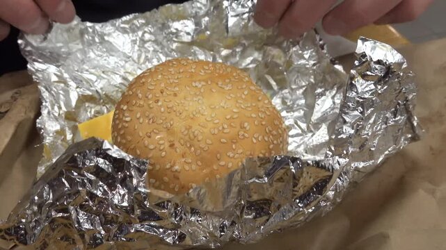 Stockholm, Sweden A man unwraps a juicy burger from a foil wrapper. 