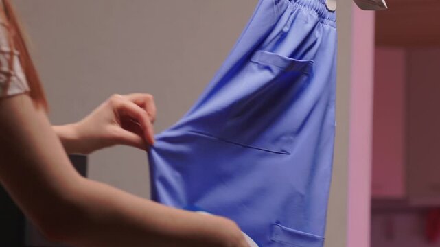 Blue shirt steaming, Blue uniform hanging while expertly steamed for wrinkle removal, Navy blue outfit on hanger being carefully steamed to remove creases professionally