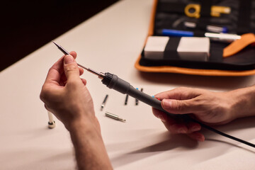 Precision soldering procedure, Hands meticulously align soldering tool precisely, Technician in closeup carefully adjusting soldering tip with safety and measurement focus