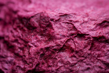 Extreme close up of purple handmade paper clay with a structure and rough texture. Paper recycling. Selective soft focus, shallow depth of field.