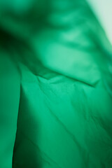 Extreme close up of green empty plastic bag background. The plastic surface is wrinkly and tattered making abstract pattern. Selective focus, shallow depth of field.