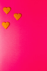 Top view of heart shaped cookies on a vibrant pink background. Dessert photography, sweet treats.