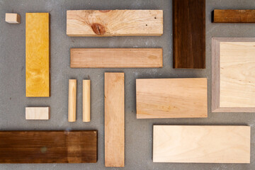 Flat lay of various wood and plywood pieces on concrete texture. Carpentry background.