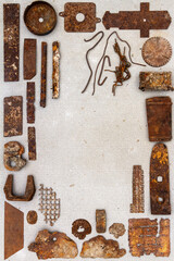 A group of various old rusty bits and pieces arranged on a concrete surface. Old rusty nuts, bolts, nails and other parts flay lay on gray background.