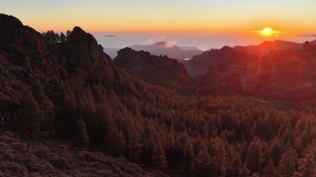 establishing drone shot of Gran Canaria volcanic mountains at sunset, aerial landscape, pine forest and volcanic rocks and the setting sun on the island of Gran Canaria, Canary Islands, Spain