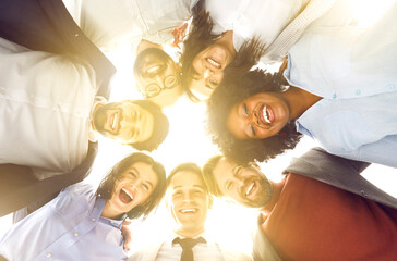 Group portrait taken from below of smiling multinational team of an office workers, standing in...