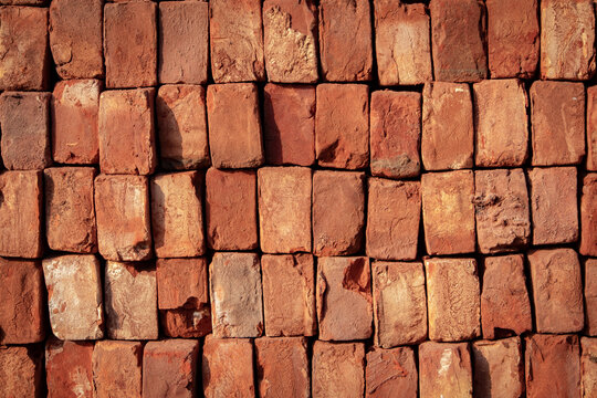 Wall texture made of stacked red clay bricks, weathered industrial background for construction