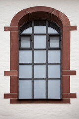 Fototapeta premium Arched window with metal grid in historic wall 