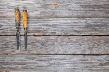 Two Worn Wood Chisels with Wooden Handles on Weathered Workbench, Top View

