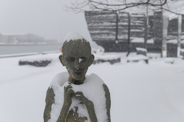 Naklejka premium front of Child Emigrant created by Irish artist Rowan Gillespie part of The Arrival, set beside the old Canada Malting silos on Eireann Quay, Toronto, during winter storm on 2026-01-15