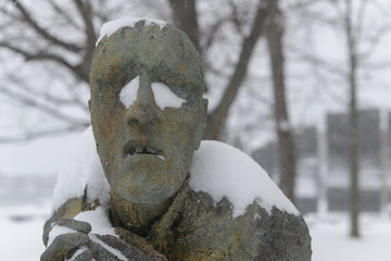 Naklejka premium front detail of Apprehensive Man created by Irish artist Rowan Gillespie part of The Arrival, set beside the old Canada Malting silos on Eireann Quay, Toronto, during winter storm on 2026-01-15
