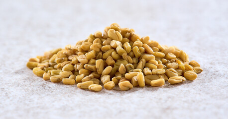 Heap of fenugreek seeds on beige background
