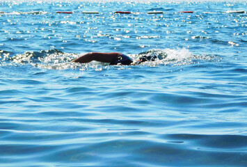 A scene on the seashore, a young person with a swimming scarf and sports shirt photographed while swimming