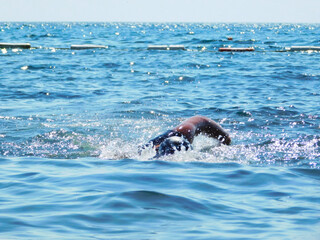 A scene on the seashore, a young person with a swimming scarf and sports shirt photographed while swimming