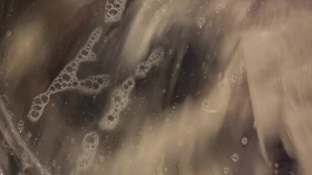 Immerse yourself in the refreshing process of cleaning clothes as water swirls and soap bubbles form in a state-of-the-art washing machine. Witness the transformations unfold in this everyday chore.