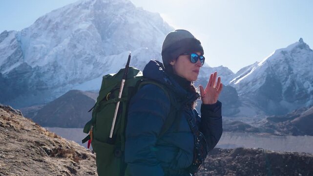 A female trekker pauses to catch her breath on a high-altitude mountain trail in the Himalayas

