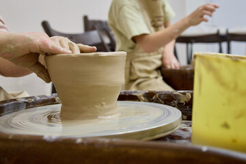 Hands shaping clay on a pottery wheel during a craft class, highlighting hands‑on learning, skill development, and the creative atmosphere of a modern artisan school.