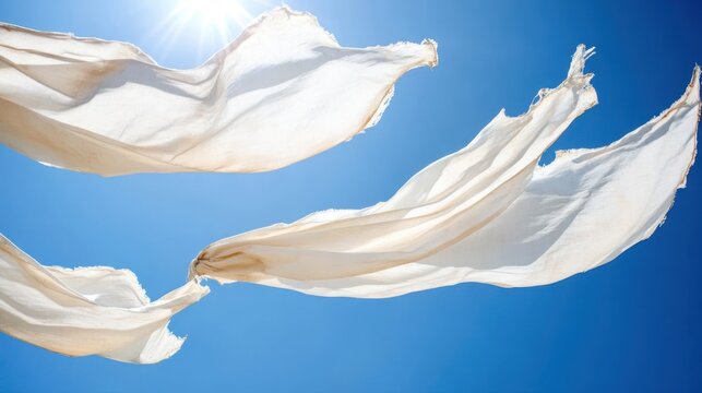Sheer white fabric billowing gently in the bright blue sky on a sunny day