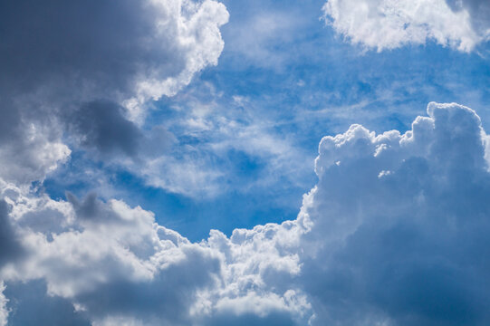 Photo of white clouds against a blue sky, the edges of which are illuminated by lateral sunlight. Weather phenomena, synoptic forecasts. Blank for artworks