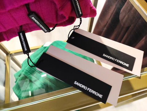 Rome, Italy - January 11, 2026: Sandro Ferrone clothing tags displayed on colorful garments in a stylish boutique, showcasing modern fashion branding and retail environment