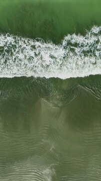 Aerial view of powerful ocean waves crashing onto the sandy Beach, dynamic movement of the sea