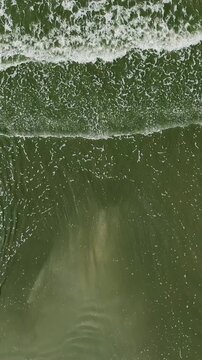 Aerial view of vibrant green ocean waves crashing on the Beach