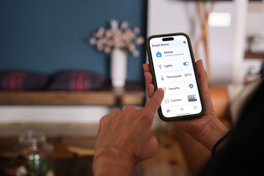 Woman using smartphone app to control lights, thermostat, security and camera in her smart home