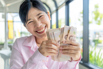 Money, Cash, Wealth, Happy Asian woman holding Thai baht banknotes, showing wealth, success, and financial happiness, close-up