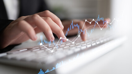A professional is engaged in data analysis in a modern office. The focus on the keyboard and data trends symbolizes growth, innovation, and productivity in the financial sector. Scalp
