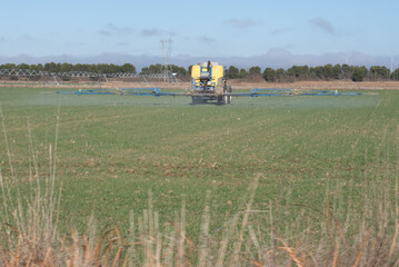 Field crop spraying with tractor and boom sprayer in agricultural landscape © Rodrigo Noceda