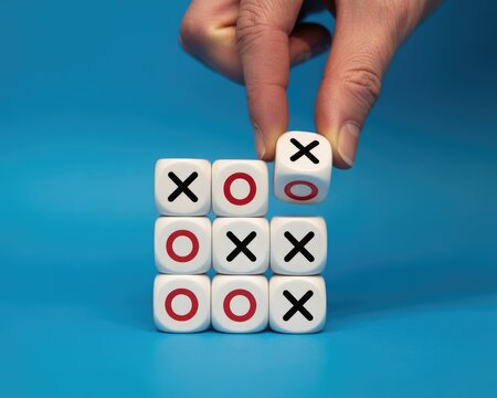 Hand placing Tic Tac Toe game piece on blue background