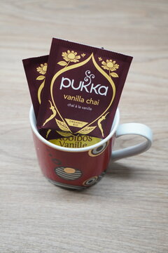 Pukka Vanilla Chai organic tea sachets in a decorative mug on a wooden surface