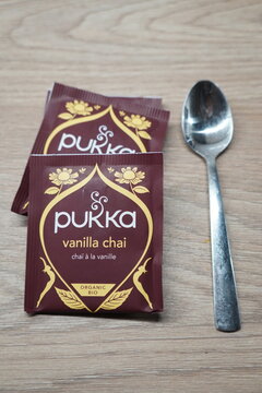 Pukka Vanilla Chai organic tea sachets and a metal spoon on a wooden table