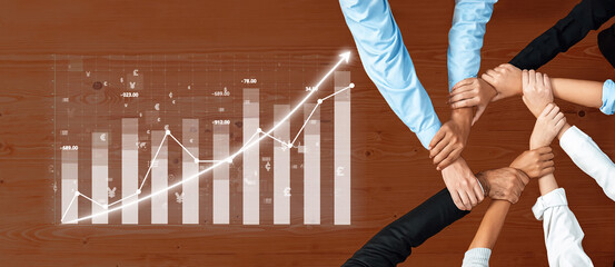A diverse group of professionals collaborates over a wooden table, showcasing hands unified around a graph representing business growth and success metrics. Axiom