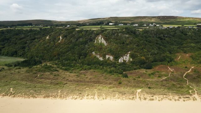 Drone footage capturing the sweeping sandy beach and turquoise waters of Oxwich Bay on the Gower Peninsula in South Wales, filmed on a bright summer day with clear skies and calm seas.