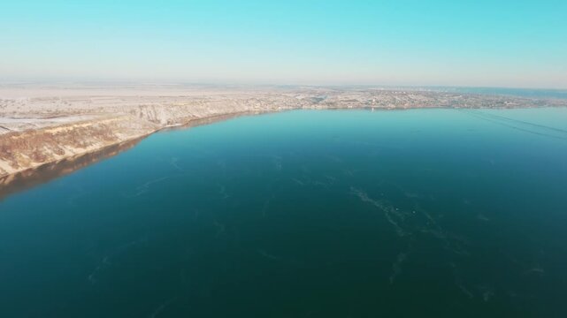 FPV drone aerial shot. Beautiful nature landscape in winter of the Dniester River with a mountain bank and clear blue sky. Moldova, Europe