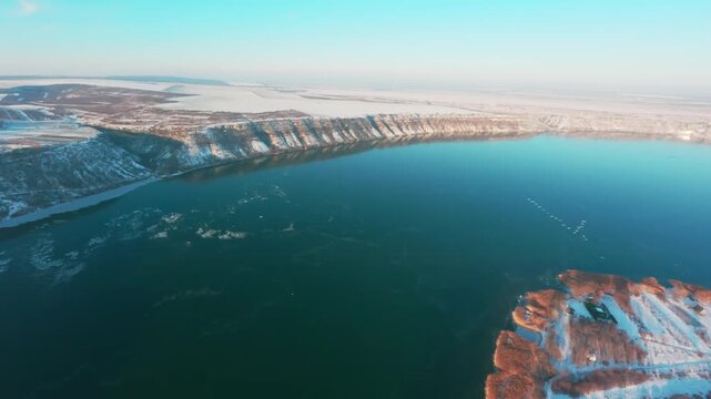FPV drone aerial shot. Wild geese fly over the river.  Beautiful nature landscape in winter of the Dniester River with a mountain bank and clear blue sky. Moldova, Europe