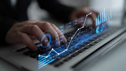 Close-up of hands typing on a laptop keyboard, with digital financial graphs and analytics overlay, representing modern business insights and data analysis. Scalp