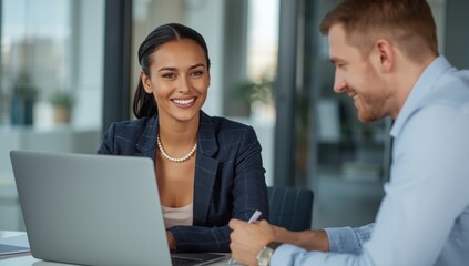 Image of a female investment advisor collaborating with a coworker at an office desk, using a laptop.png