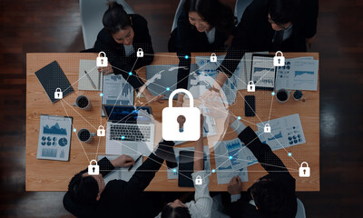 A top-view image of a diverse business team collaborating on security strategies using data charts and global network icons on a wooden table. Gantry