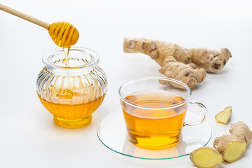 Hot ginger tea with honey and fresh ginger roots on a plain surface during the daytime