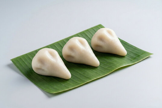 Traditional steamed Mera Pitha (Dola Pitha) rice cakes on green banana leaf