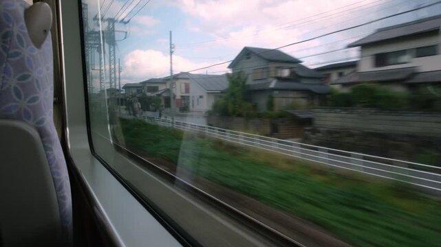 Japanese landscape with traditional houses and rice fields passing by from a high speed train window