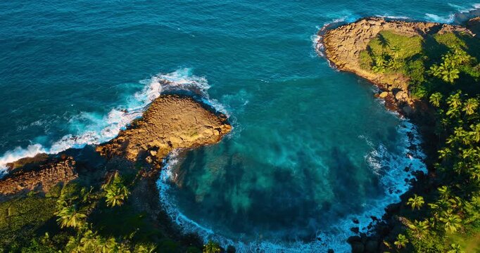 Waves of blue ocean waterscape roll to the shore. Lush greenery covers the coast. Manati, Puerto Rico. Aerial view.