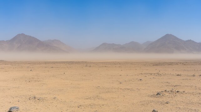 Dust particles creating a hazy veil over an arid desert landscape with mountains in the distance