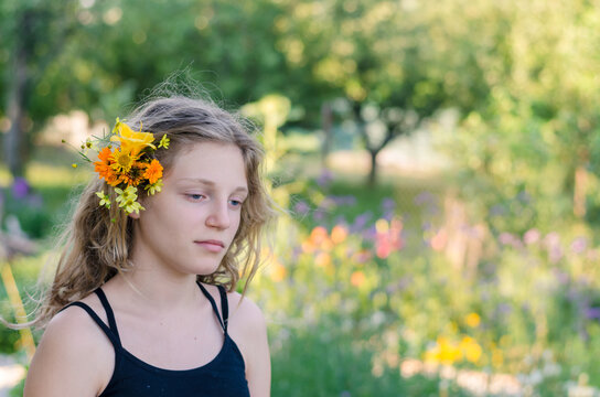 emotional portrait of teenage girl with orange and yellow flowers in hair