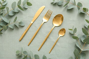 gold cutlery set with eucalyptus leaves on green background high quality professional detailed modern elegant stylish clean crisp vibrant colorful digital